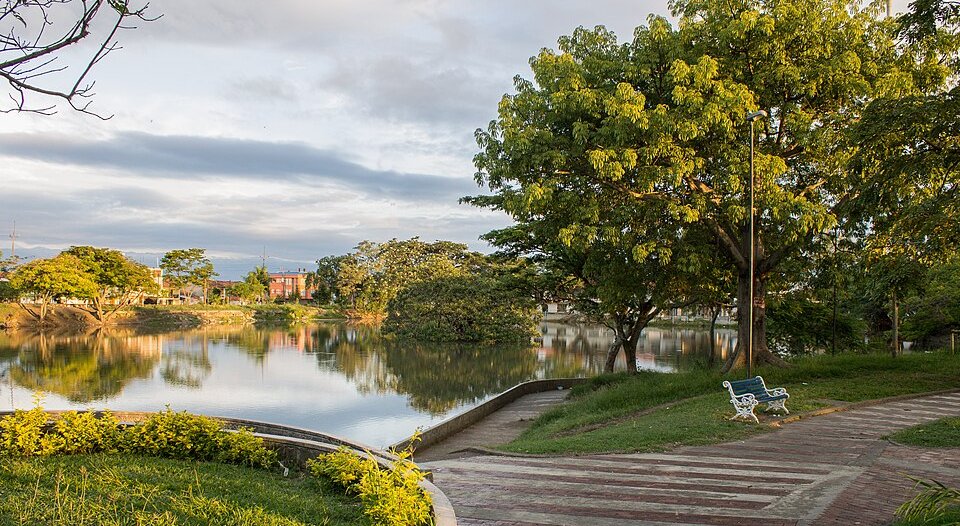 Fotografía del Lago Chilicote, con arboles, senderos, y bancas durante un día nubloso. Credito a: César Rengifo